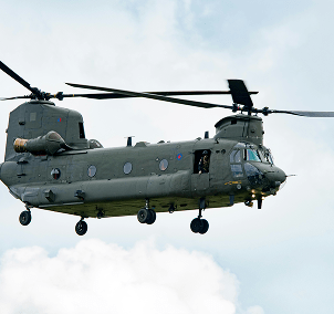 "Military transport helicopter in flight against a cloudy sky"
