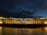 Parliament House in Canberra illuminated at night, reflecting in the water feature in front